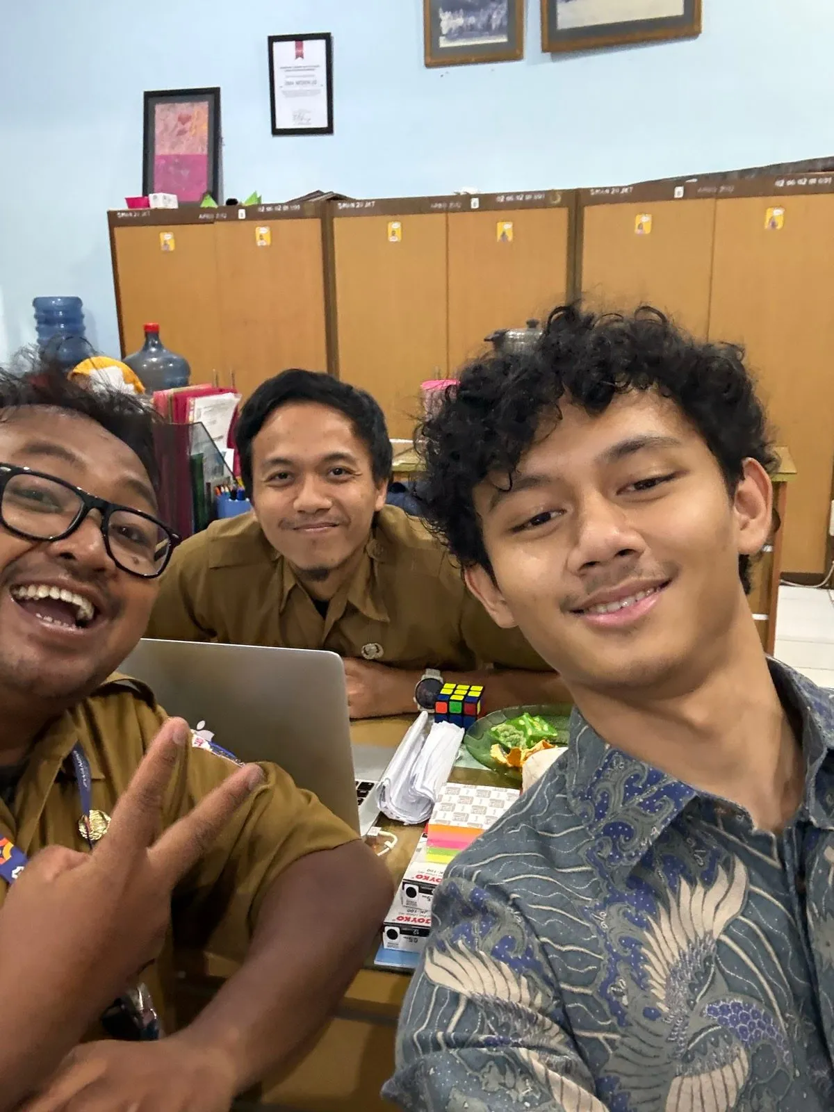A selfie of a Pikira founder with two teachers at a school office desk.
